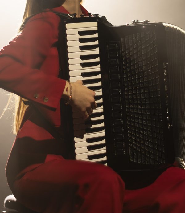 Close up of hands on an accordion keyboard with an ccordionist in a red suit.