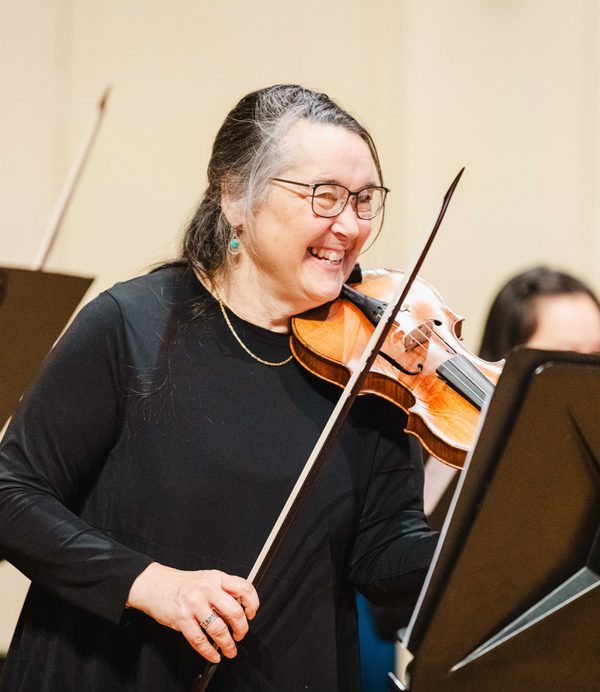 Margaret Faultless playing violin and smiling.
