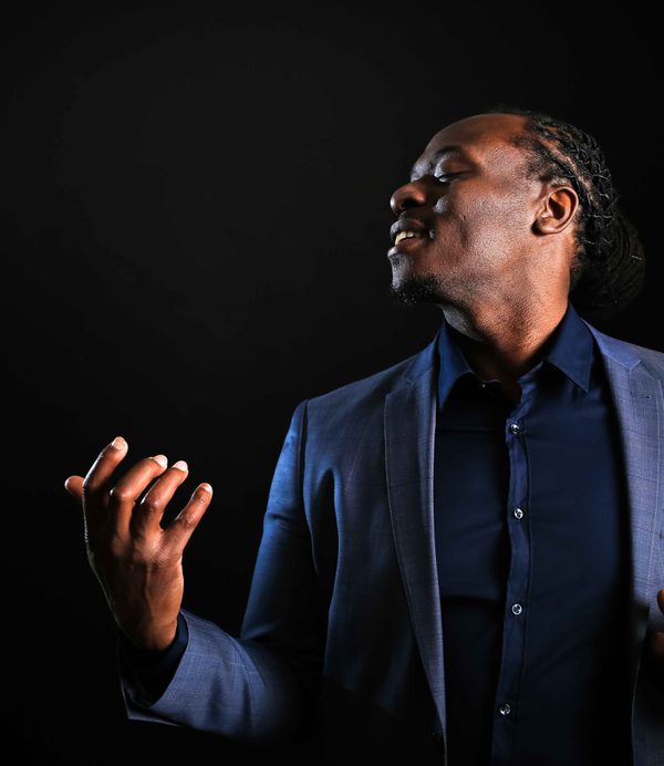 Femi Temowo poses expressively against a black backdrop.