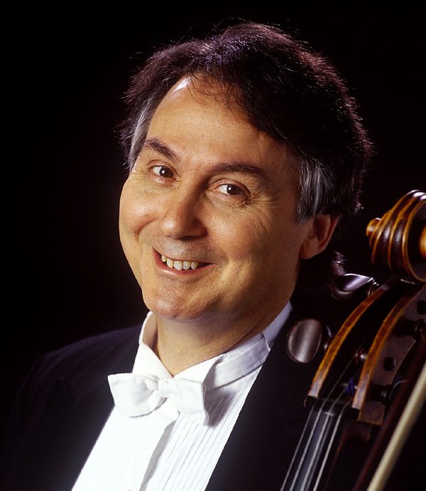Ralph Kirshbaum holds a cello and smiles to camera.