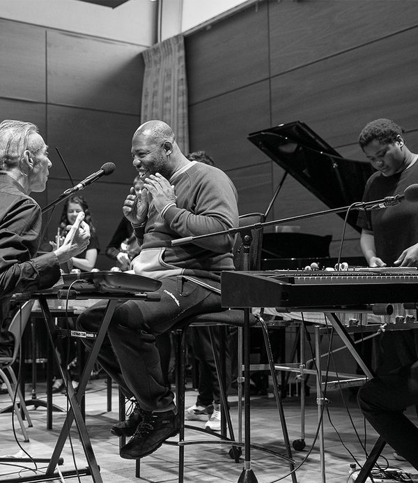 A tutor instructing a keyboard player.