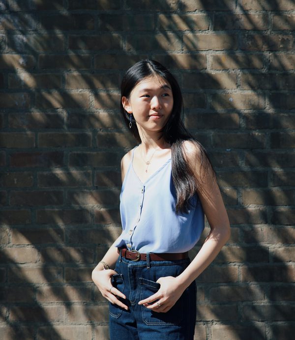 Cherry Ge stands in front of a wall with hands in pockets.
