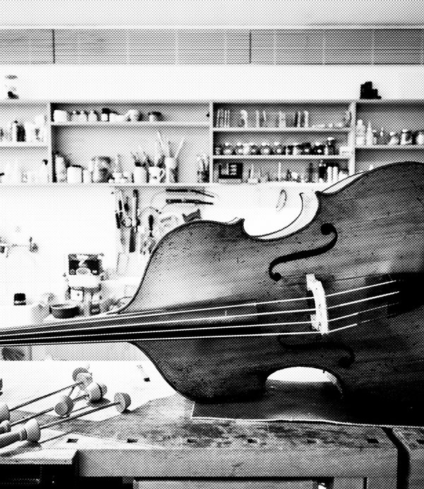 black and white image of a cello in the museum luthier workshop's table