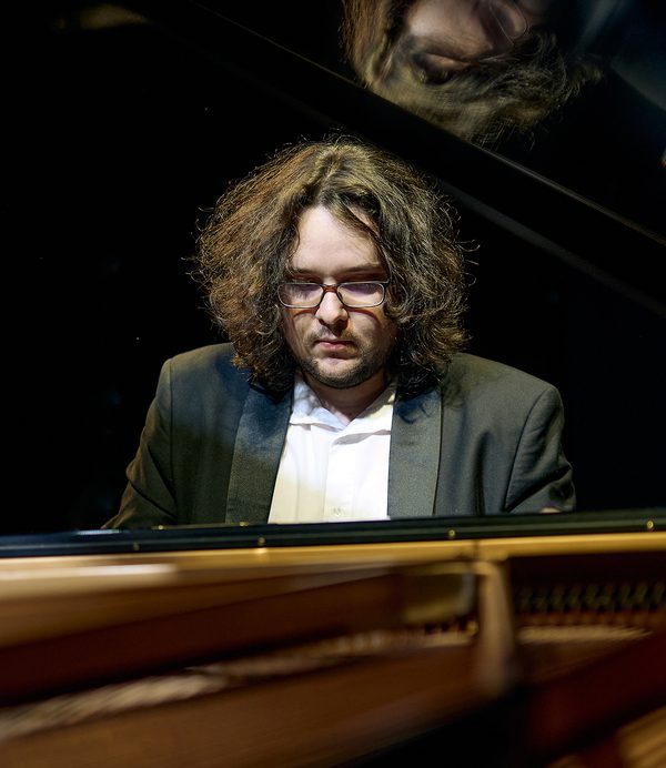 Jakub Kuszlik sitting at a piano