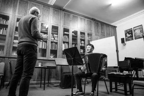 An accordion student and teacher in a lesson.