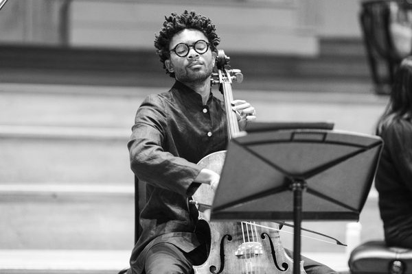A cellist practising while reading from a music stand.