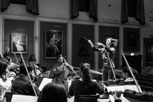 A conductor and ensemble in rehearsal.