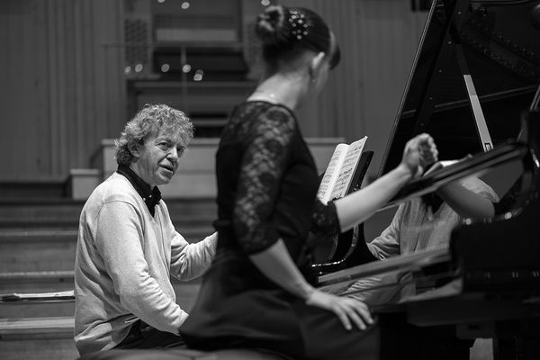 Two pianists together at a piano keyboard.