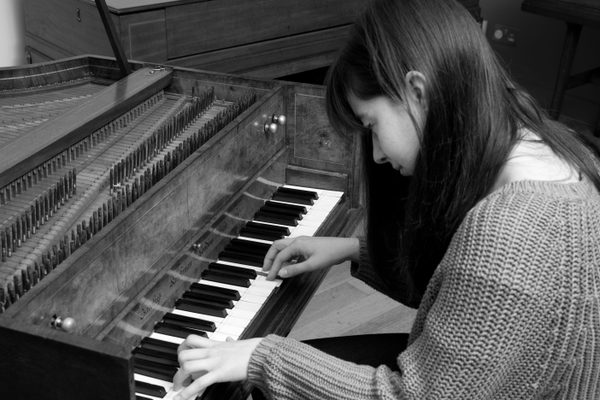 A harpsichord player at the keyboard, viewed from over the shoulder.