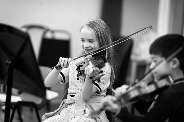 A young violin player smiles in a lesson.