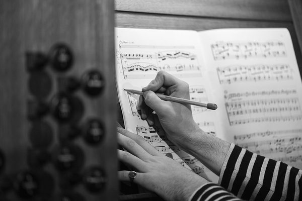 Hands writing on sheet music.