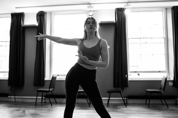 A musical theatre performer in rehearsal, striking a pose.