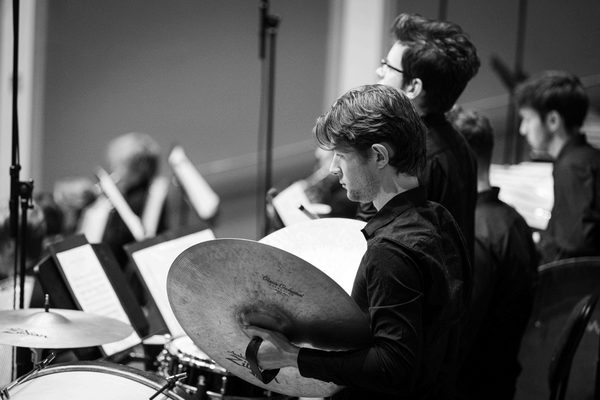 A cymbalist, viewed from over the shoulder.