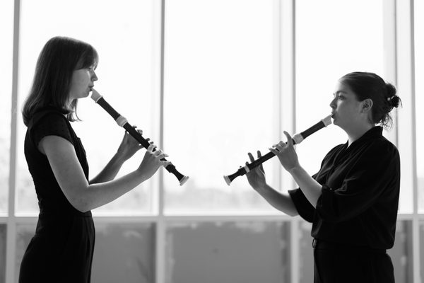 Two recorder players face each other.