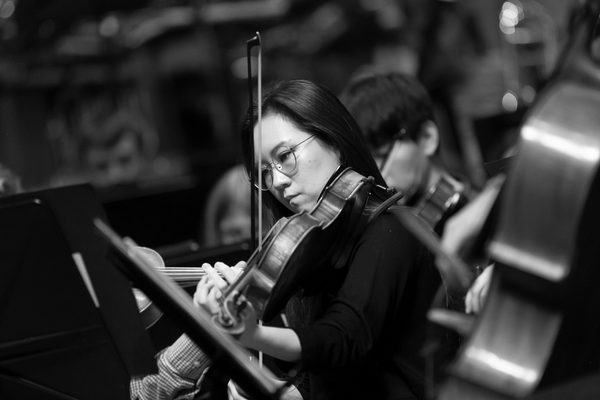 A violinist plays intensely in concert.