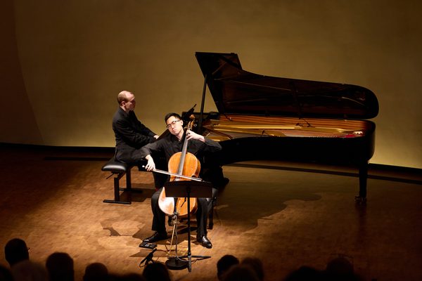 A pianist and cellist perform on stage.