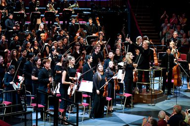 An orchestra of 46 musicians and conductor Edward Gardner stand on stage at the Royal Albert Hall