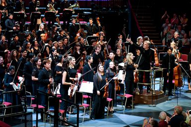 An orchestra of 46 musicians and conductor Edward Gardner stand on stage at the Royal Albert Hall