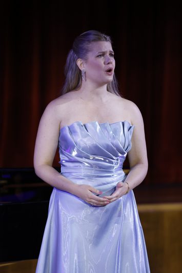 A woman in a blue dress stands on stage singing