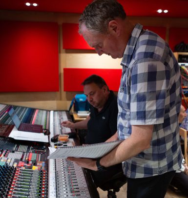 Two people look over a sound board in Abbey Road Studios