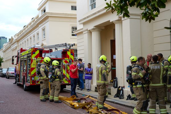 A team of firefighters and a firetruck pictured outside a white building