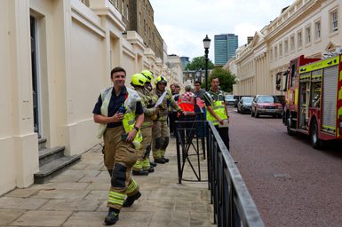 A team of firefighters on a pavement outside a building
