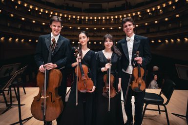 Students hold their string instruments on stage at Carnegie Hall