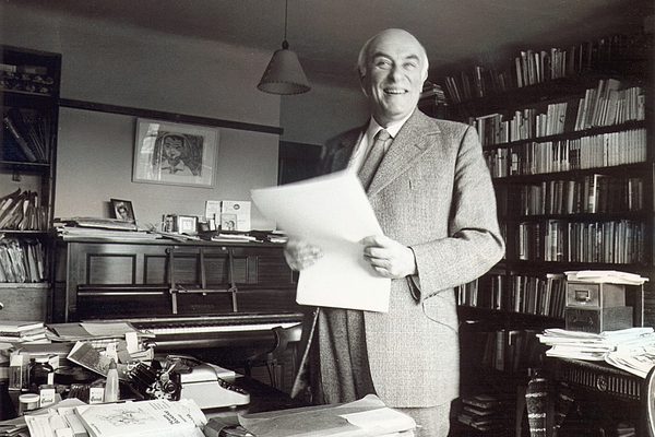 Black and white portrait of Alan Bush holding paper and smiling