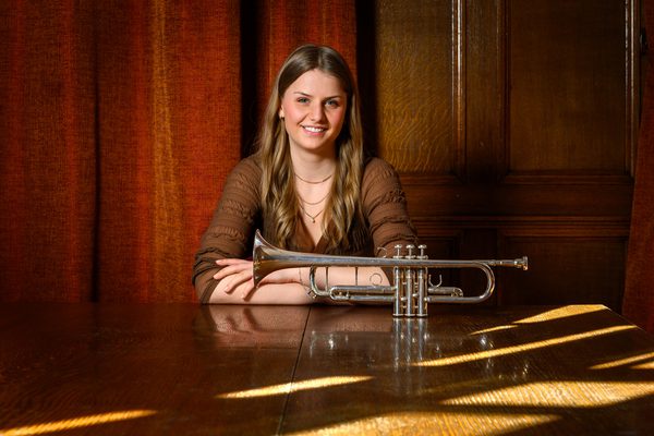 Ellinor Bengtson pictured smiling to camera with a trumpet on the table in front of her