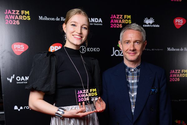 Emma Rawicz stands on the Jazz FM Awards red carpet holding an award. She is standing next to Martin Freeman.