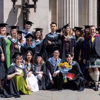 A large group of students posing for a photo, wearing mortarboards and ceremonial gowns, outside Freemason's Hall, London.