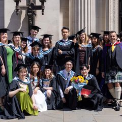 A large group of students posing for a photo, wearing mortarboards and ceremonial gowns, outside Freemason's Hall, London.