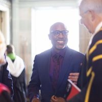 Alexis Ffrench pictured in conversation with a group of people, smiling.