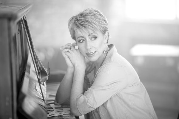 Nikki Iles sits at a piano keyboard, looking off camera