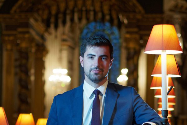 Portrait of James Orford looking at the camera. He is in a cathedral.