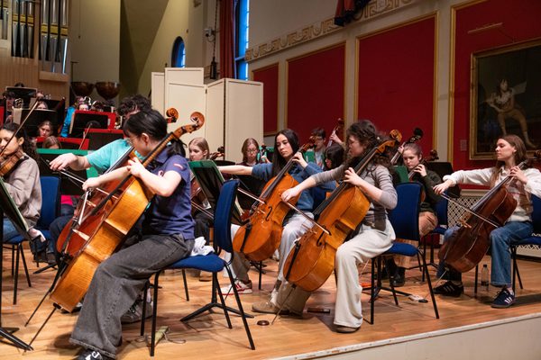 Junior Academy students play strings instruments on stage in the Royal Academy of Music Duke's Hall