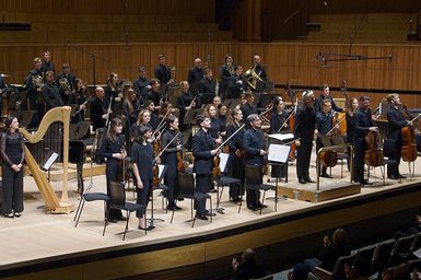 An orchestra on stage taking bows.
