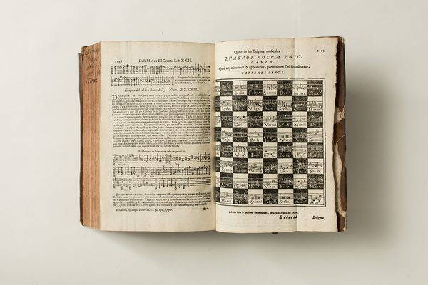 An ancient book lies open, showing text and musical symbols.