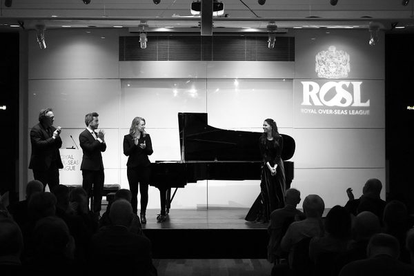 Four pianists stand on the ROSL stage in front of a piano