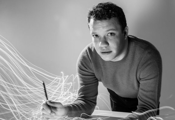 A black and white portrait of Ryan Bancroft holding a baton