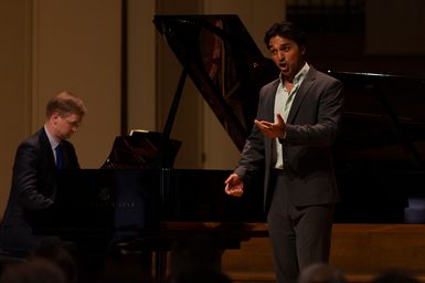 An opera singer performs on stage with a piano accompanist