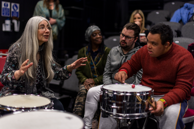 Dame Evelyn Glennie talks with a member of the City Lit Percussion Orchestra, who is playing the drums