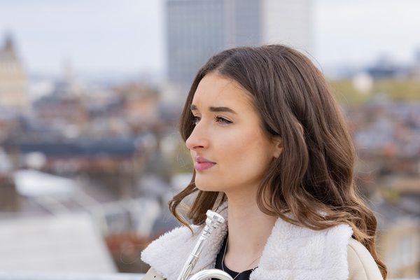 Holly Clark sits on the rooftop of the Royal Academy of Music holding her trumpet.