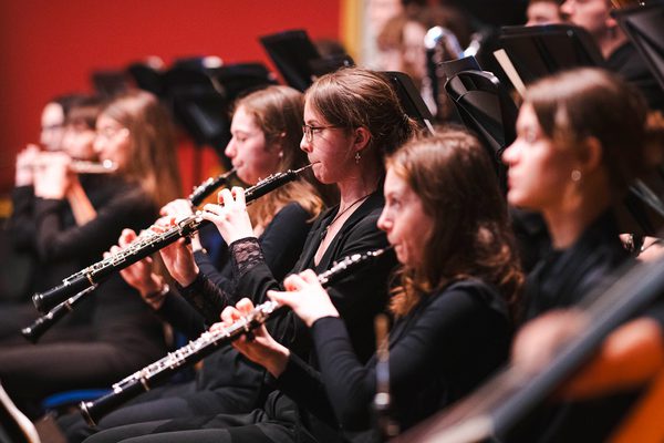 Three oboists performing as part of a symphony orchestra
