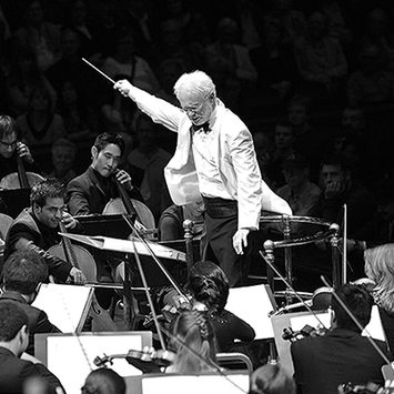 A conductorpoints a baton skyward.