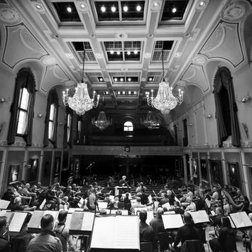 A concert hall with a symphony orchestra on stage in rehearsal.