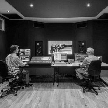 Two sound engineers sit at a recording console.