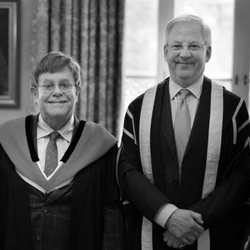Sir Elton John and Professor Jonathan Freeman Attwood CBE smile to camera.