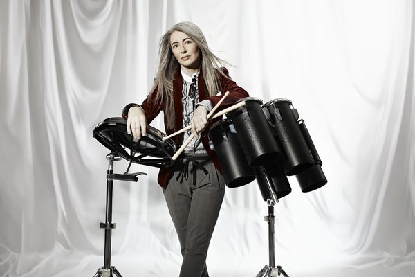 Evelyn Glennie stands at a drum kit.