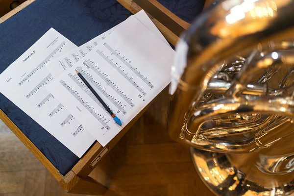 Sheet music on a chair next to a trombone.